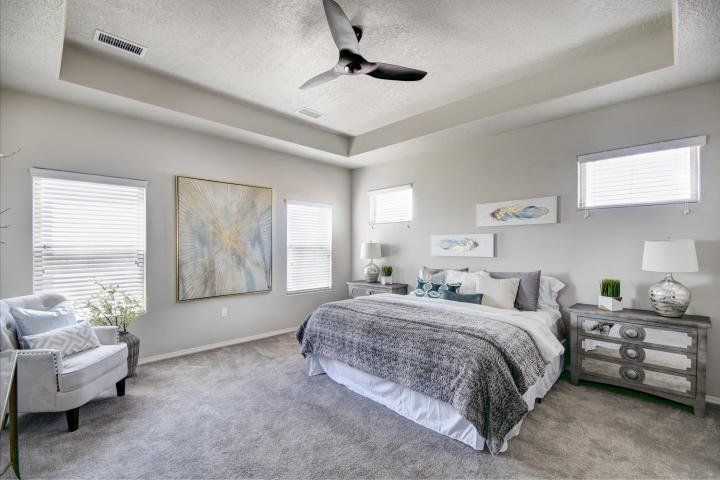 A bedroom with a bed , chair , nightstand and ceiling fan.