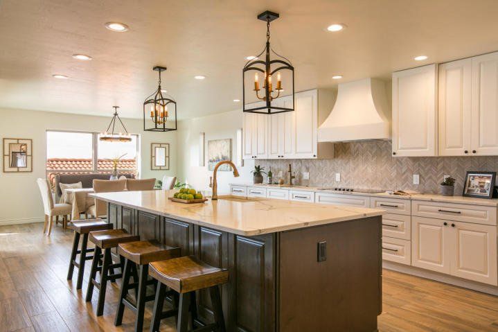 A kitchen with white cabinets and a large island with stools.