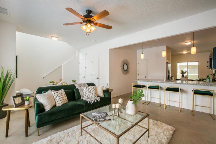 A living room with a green couch , a coffee table , and a ceiling fan.