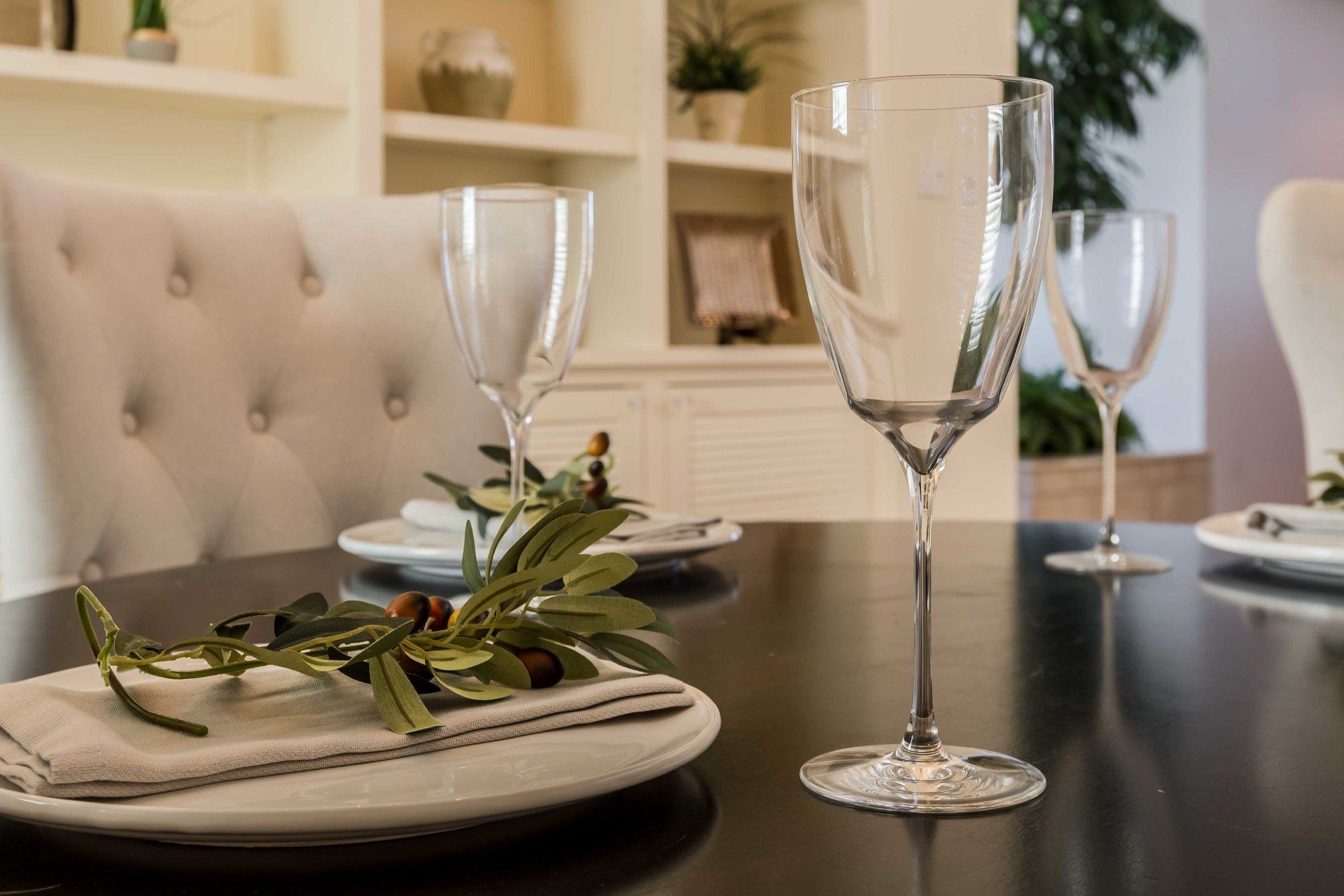 A dining room table with plates and wine glasses on it.