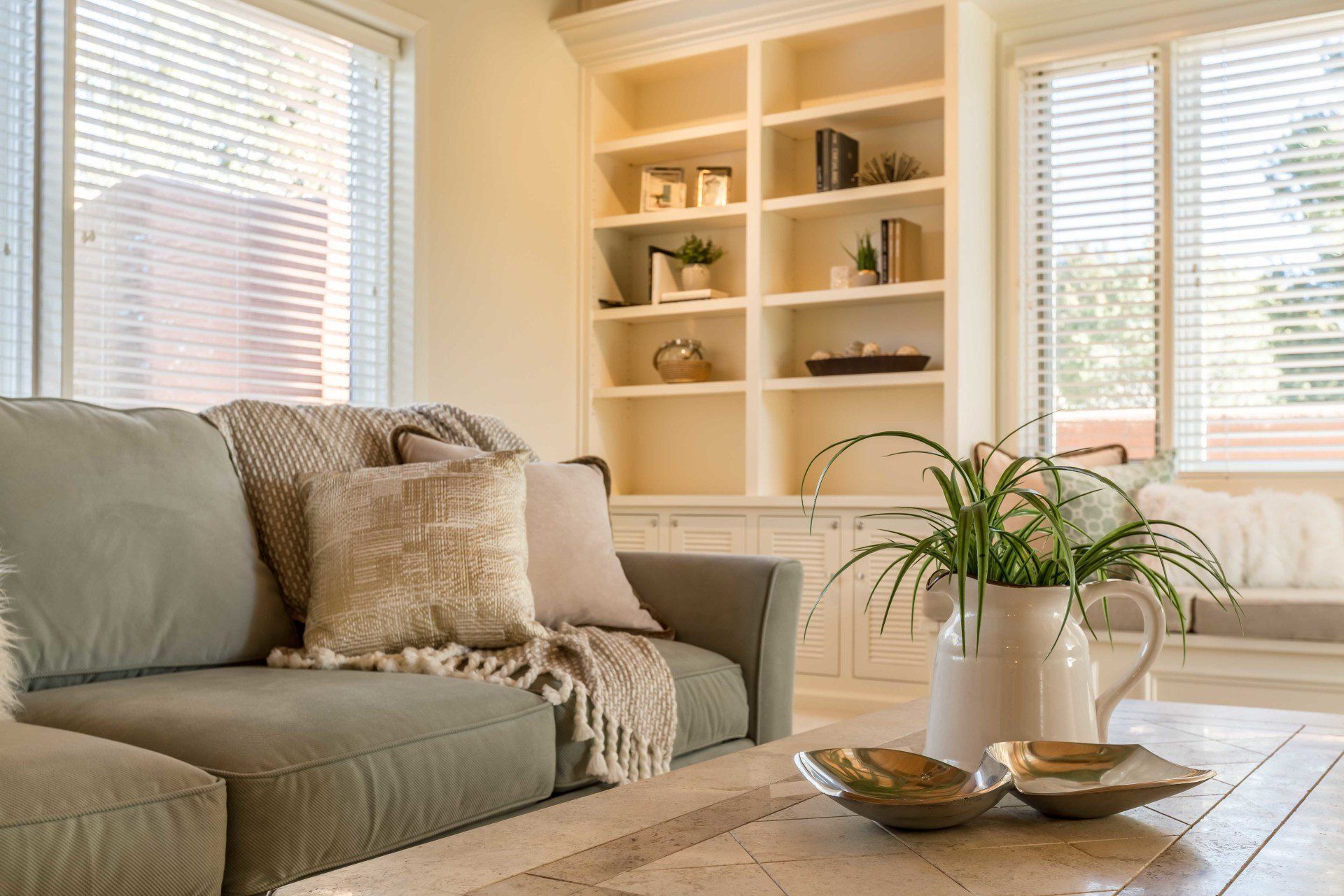 A living room with a couch , coffee table , and shelves.