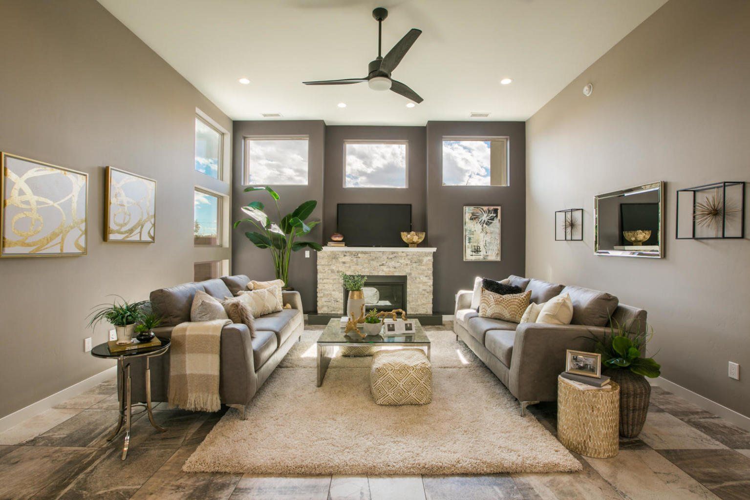 A living room with two couches , a fireplace and a ceiling fan.