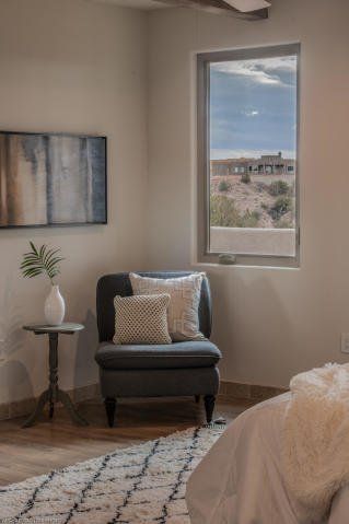 A bedroom with a chair , table , and window.
