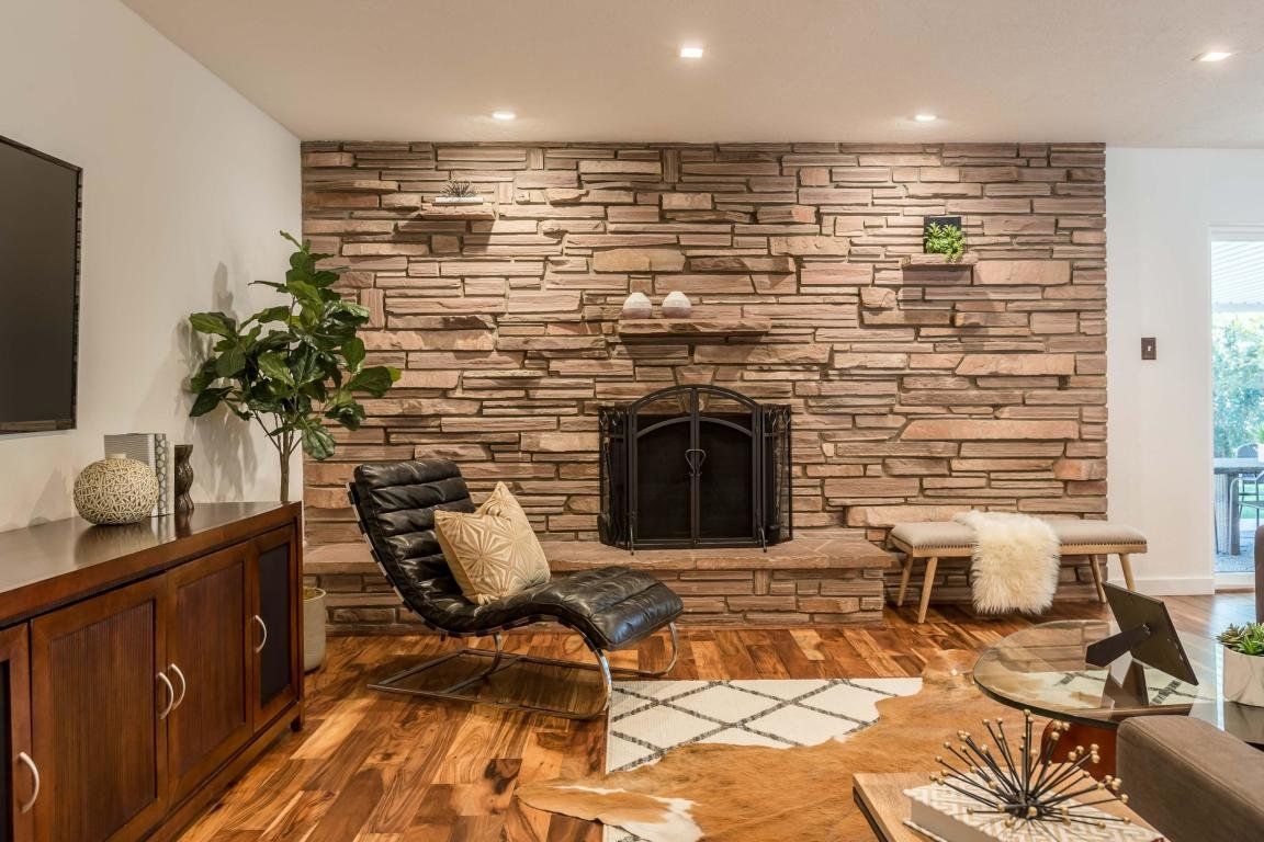 A living room with a fireplace , chair and television.