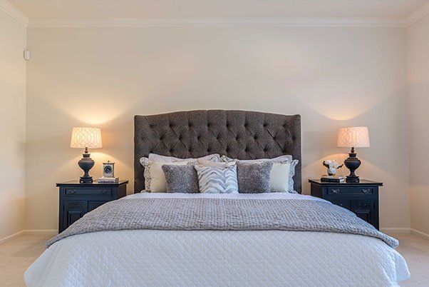A bedroom with a bed , two nightstands and two lamps.