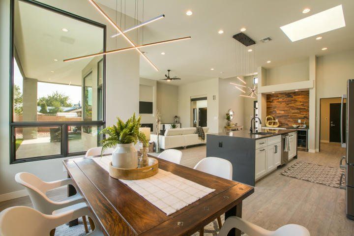 A dining room table and chairs in a modern home with a large window.