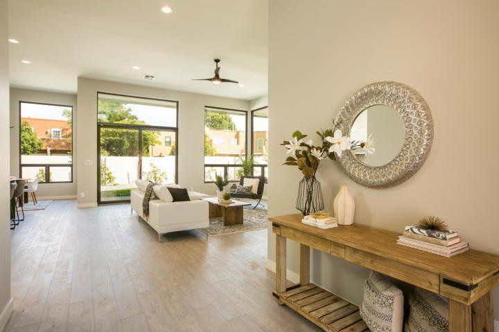 A living room with a couch , table , mirror and ceiling fan.