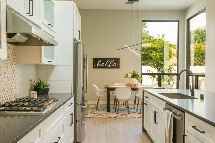 A kitchen with white cabinets and a sign that says hello