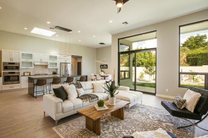 A living room with a couch , chair , coffee table and sliding glass doors leading to a kitchen.