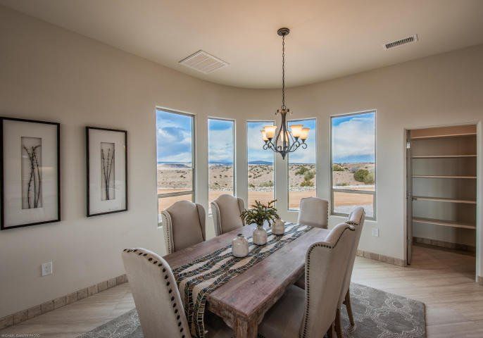A dining room with a wooden table and chairs and a chandelier.