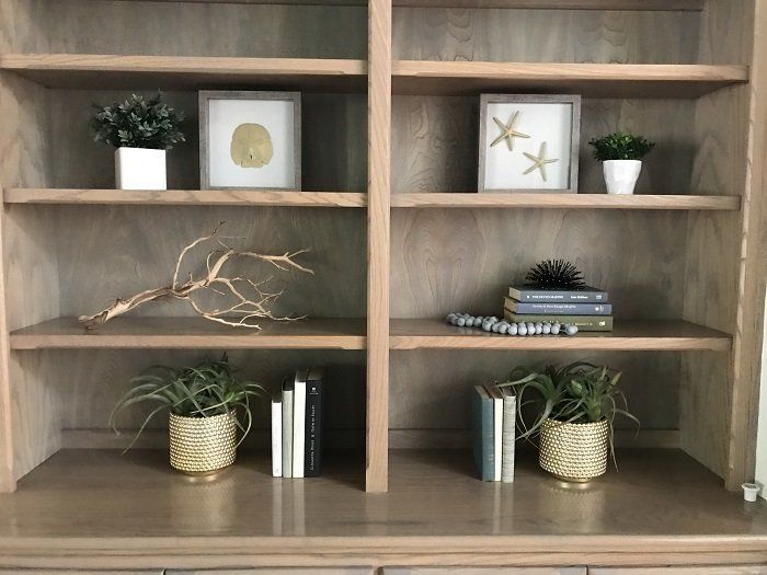 A wooden bookshelf with plants and books on it.