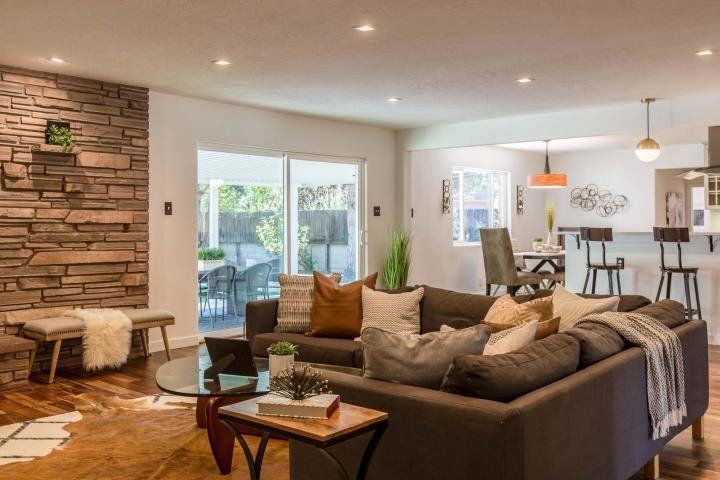 A living room with a couch , table , chairs and a stone wall.