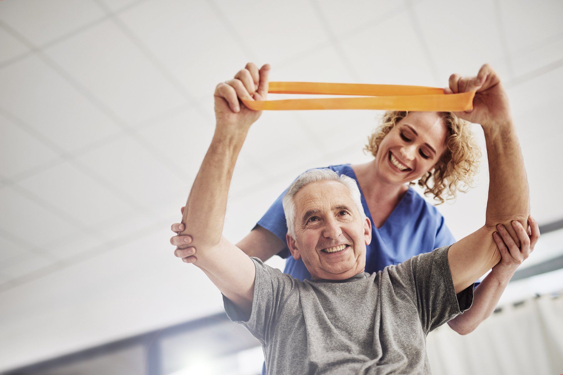 A nurse is helping an elderly man with a resistance band.