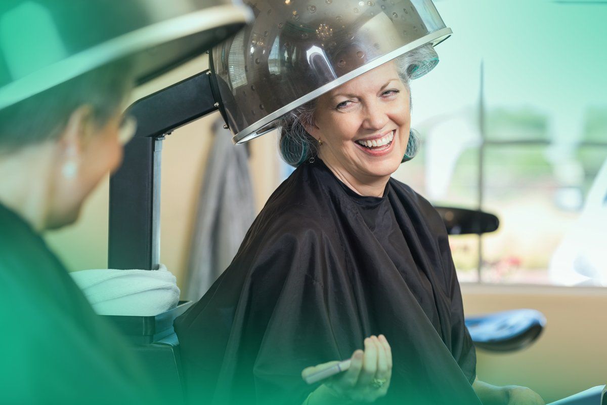 An older woman is getting her hair cut at a salon.