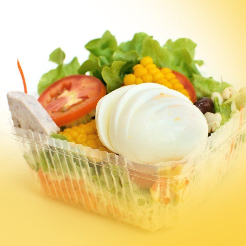 A plastic container filled with vegetables and a hard boiled egg