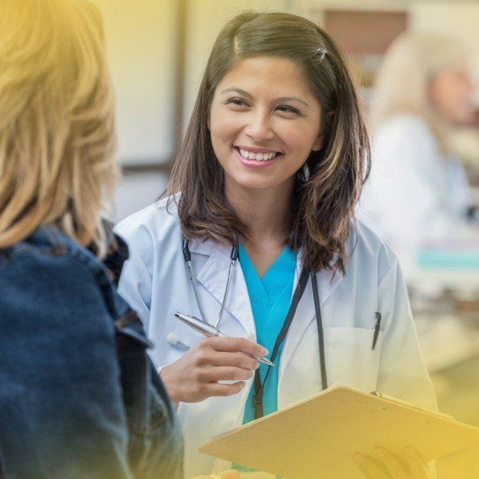 A female doctor is smiling while talking to a patient.