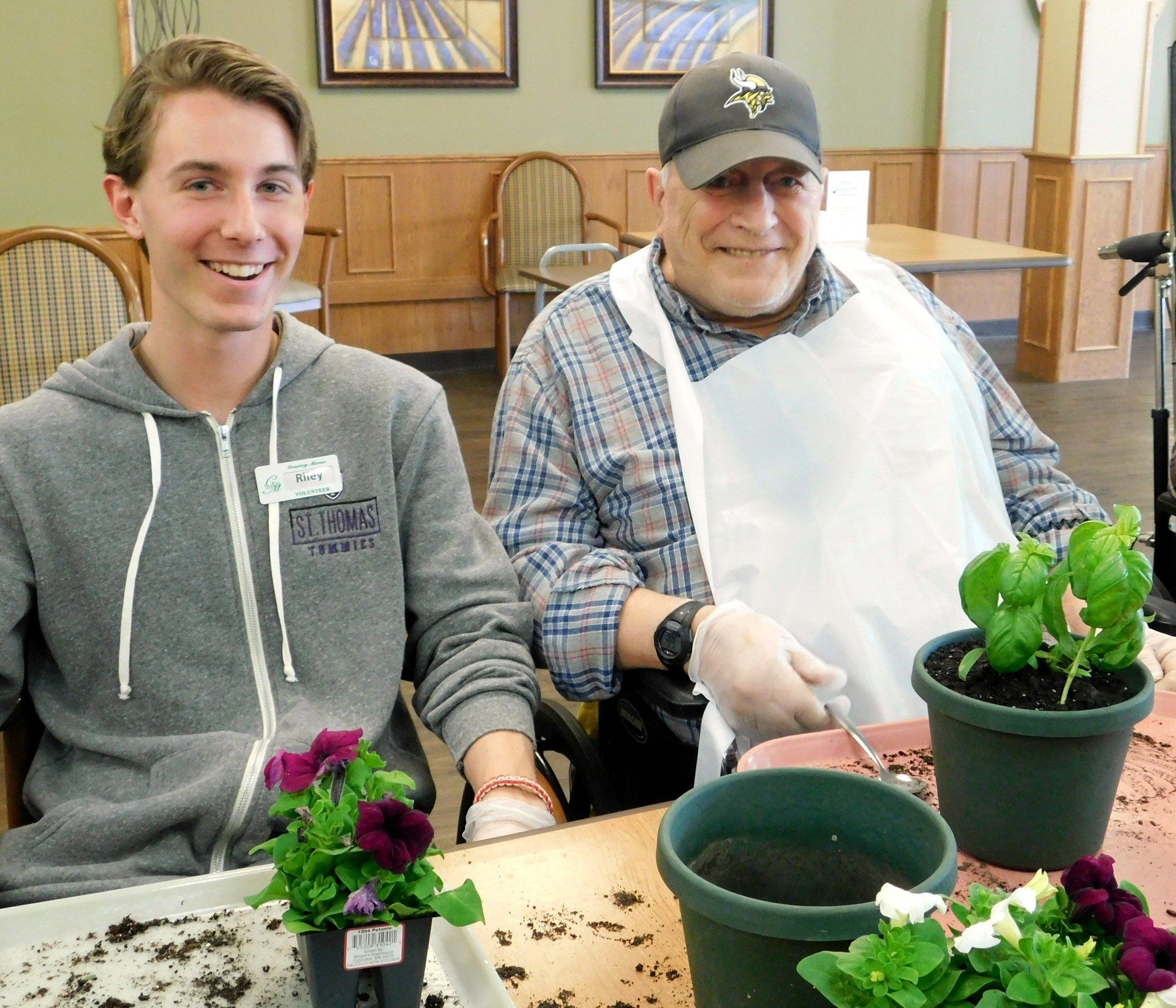 Country Manor resident and volunteer are gardening at a table with potted plants