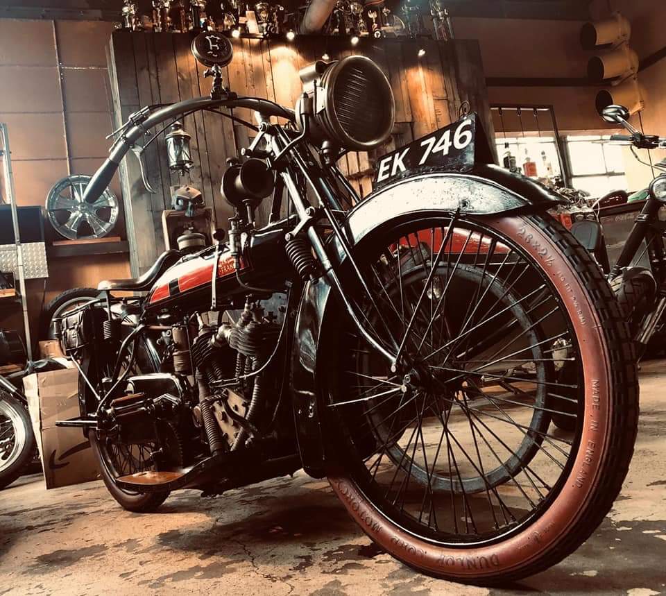 An old motorcycle with a red tire is parked in a garage.