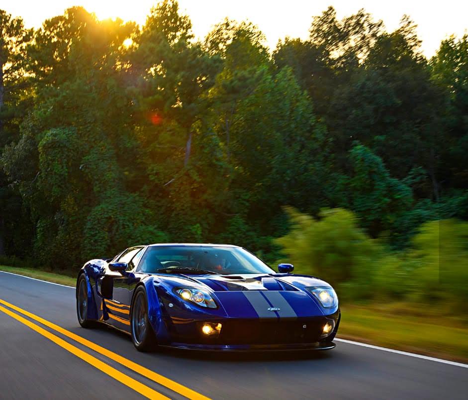 A blue sports car is driving down a road