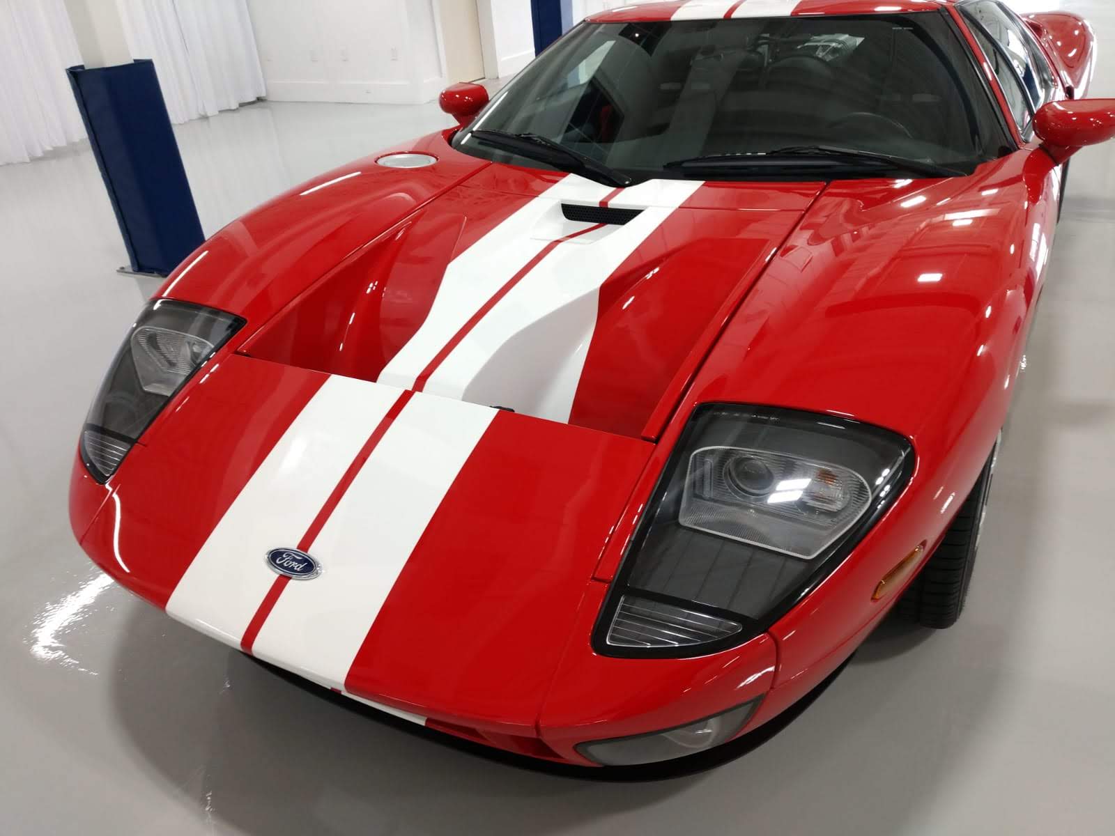 A red sports car with white stripes is parked in a garage