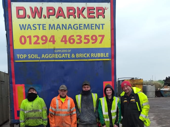 Team standing below sign for D.W Parker