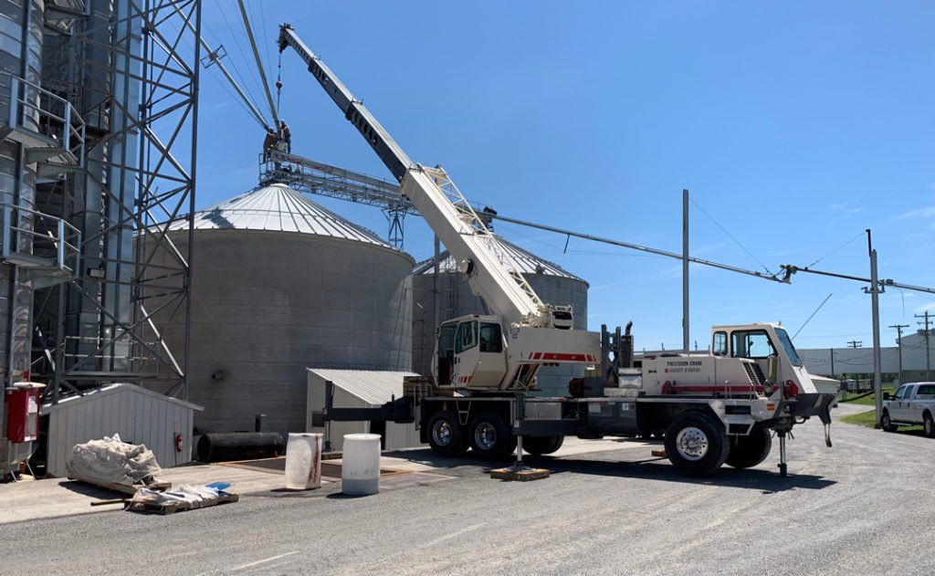 A truck with a crane attached to it is parked in front of a building.