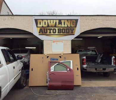 Dowling Auto Body shop front with car doors and vehicle parts displayed outside in the driveway