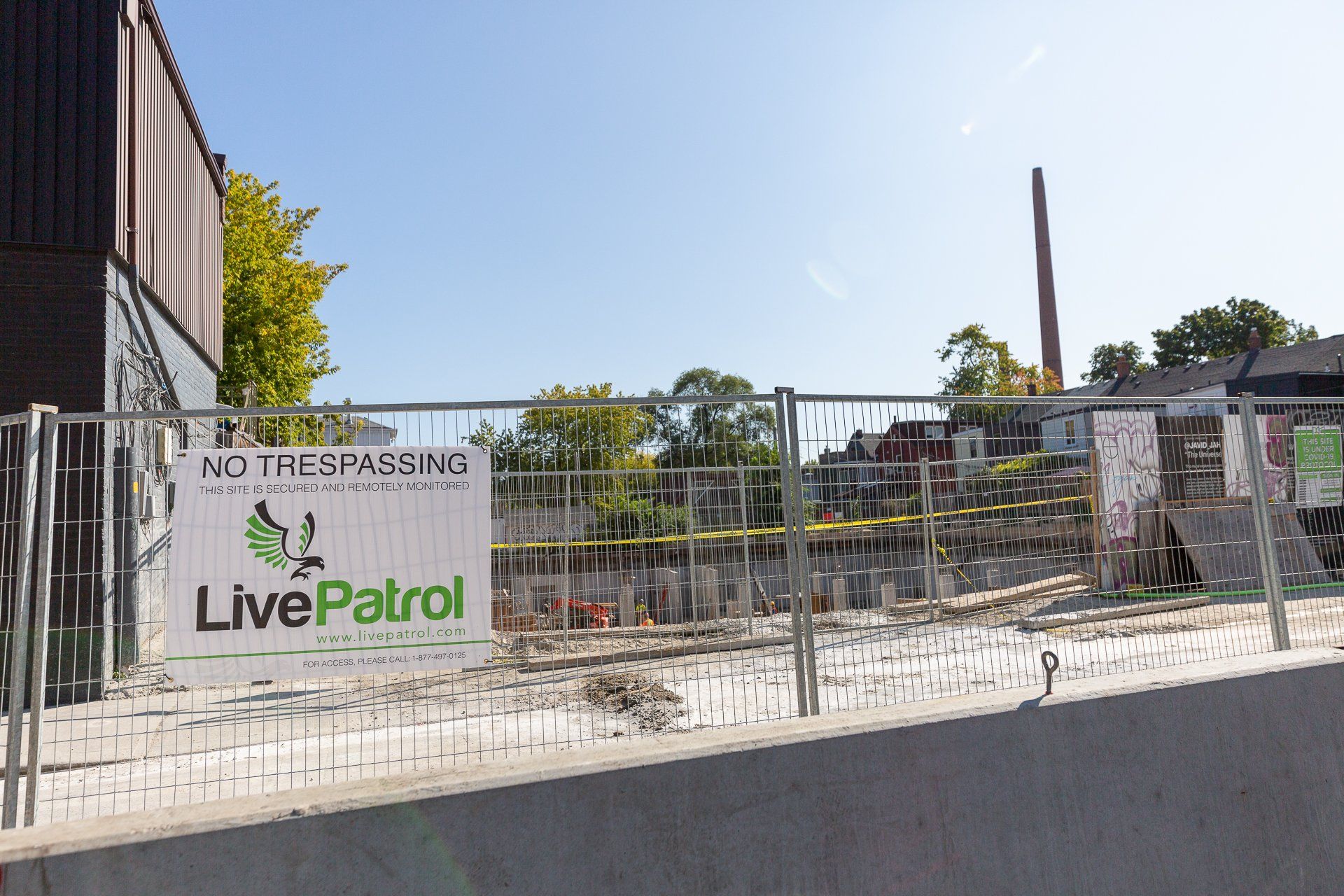 A chain-link fence surrounds a construction site featuring a 