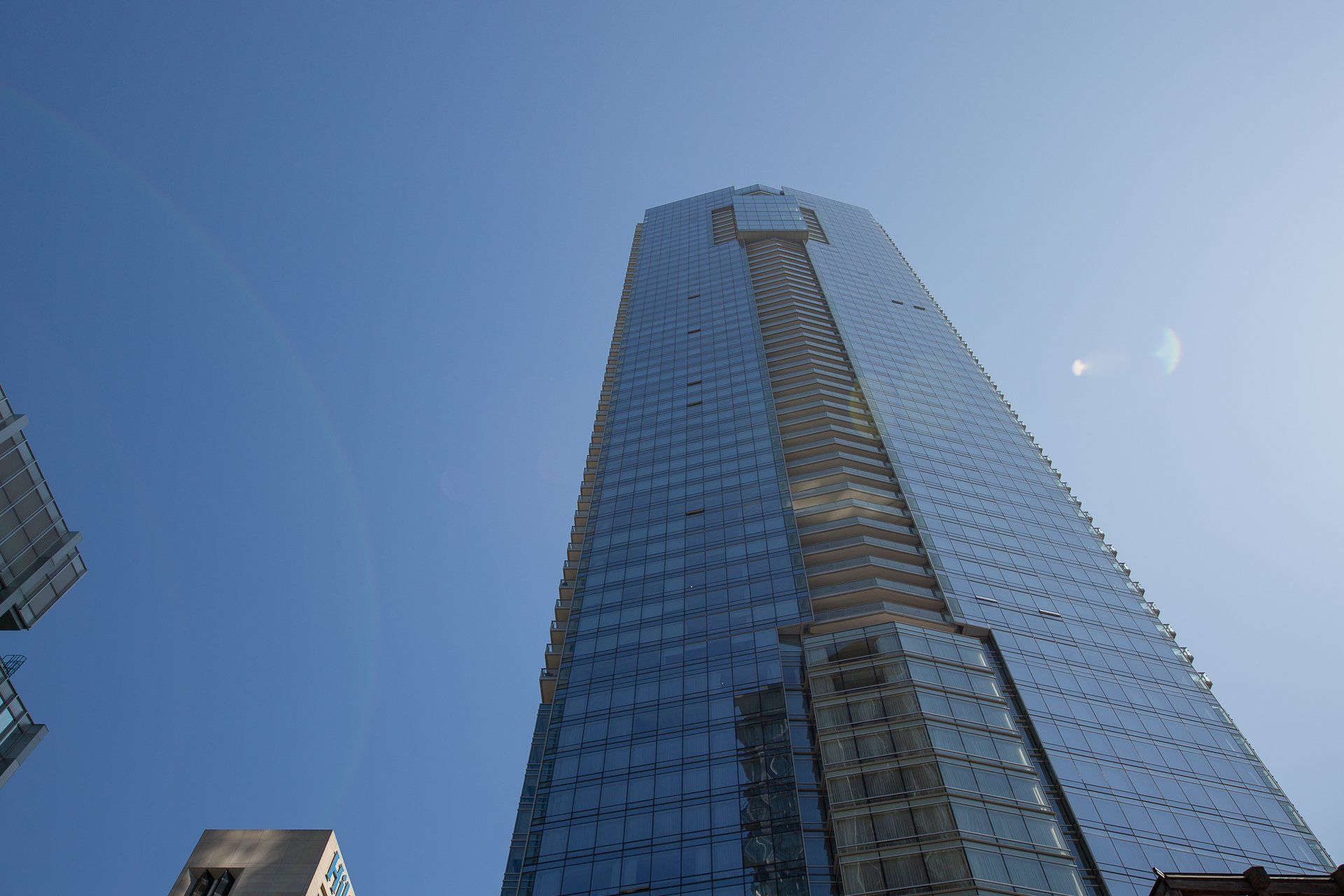 A low-angle view of a modern glass skyscraper rising into a clear blue sky.