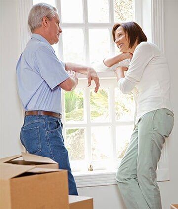 Couple standing by window with moving boxes — Moving Company in Altoona, PA