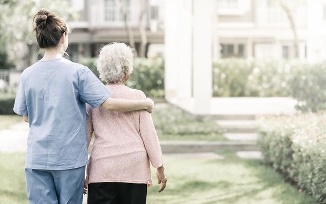 Carer with arm around older woman outdoors