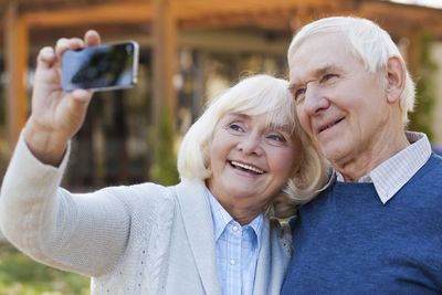 Independent Living — Senior Couple Taking Picture In Park in Glenview, IL Independent Living — Senior Couple Taking Picture In Park in Glenview, IL