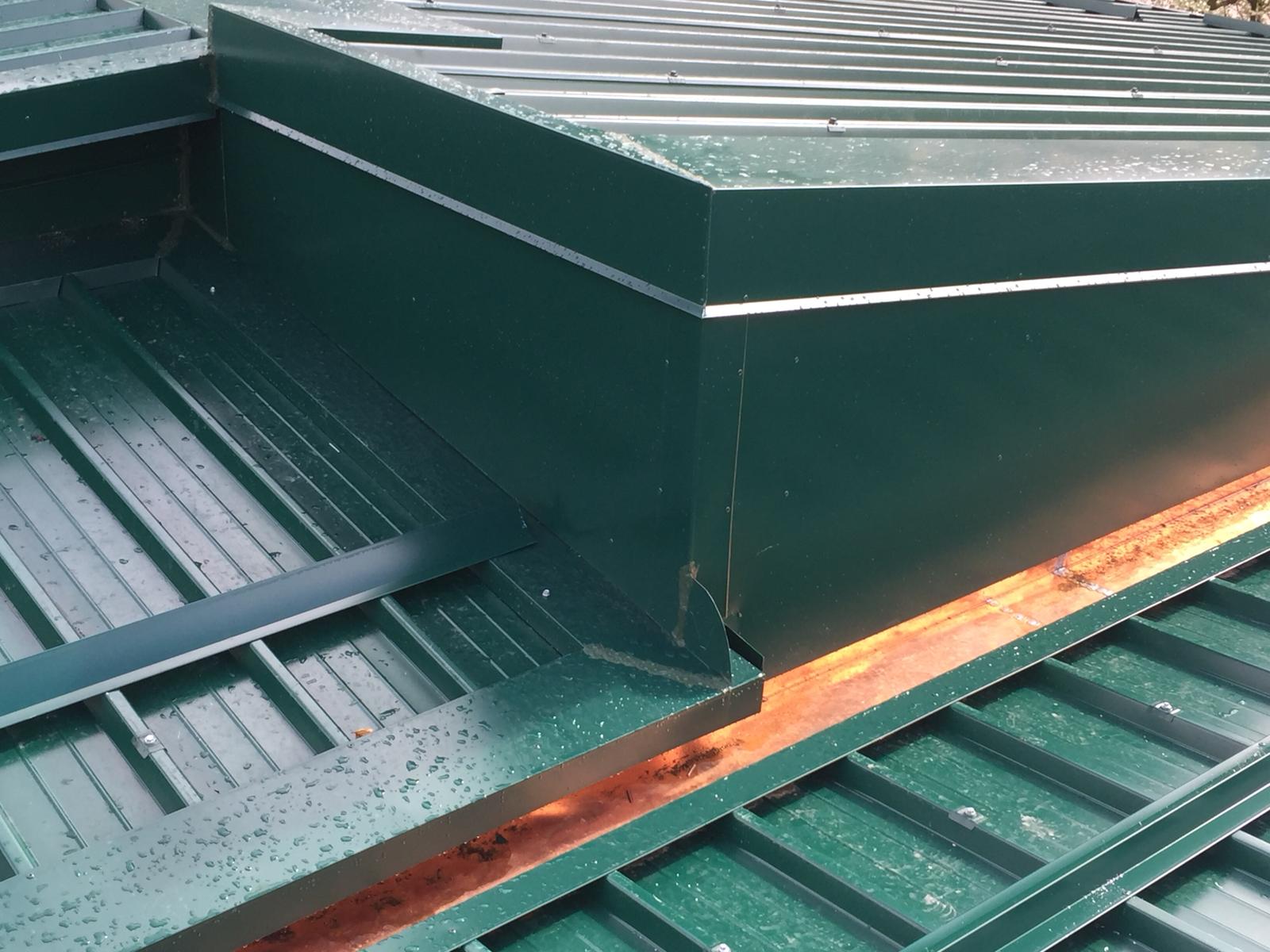Un primo piano di un tetto in metallo verde con finiture in rame
