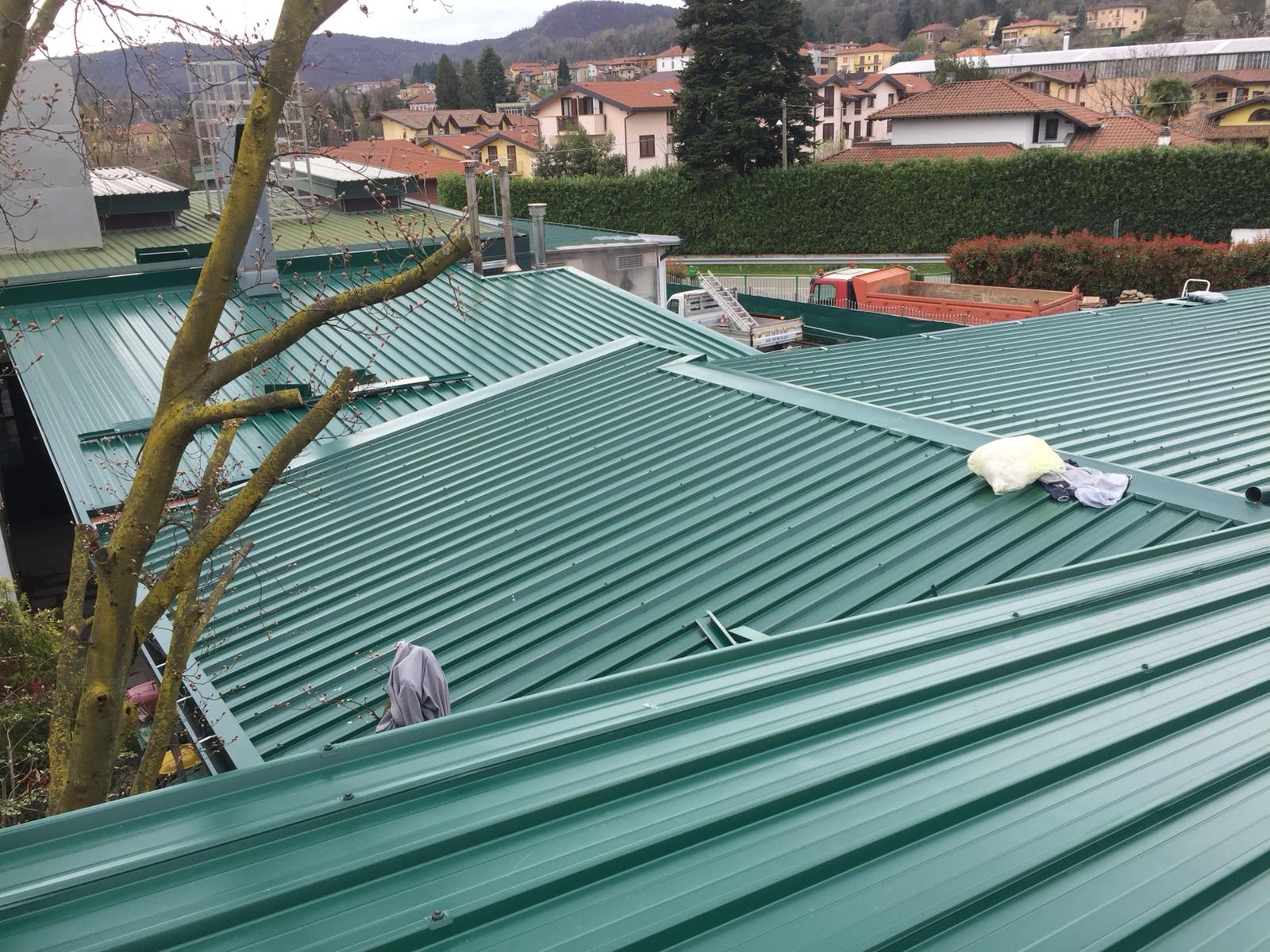 Un tetto di metallo verde con un albero sullo sfondo.