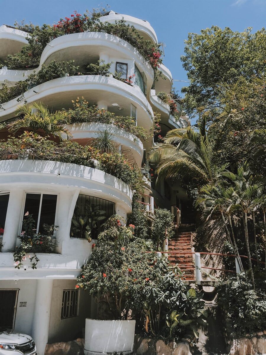 A Large White Building With A Lot Of Balconies Surrounded By Trees — Lynams Landscapes Pty Ltd in Cosgrove, QLD