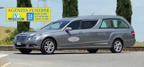 Carro funebre accanto la insegna del negozio