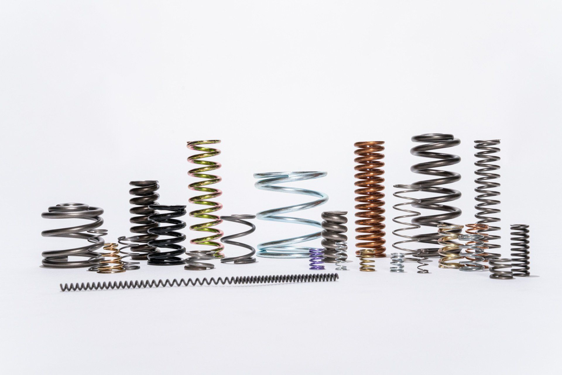 A bunch of different types of springs are lined up on a white surface.