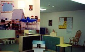 Empty classroom with tables, chairs, bulletin boards, and a desk in a small meeting room