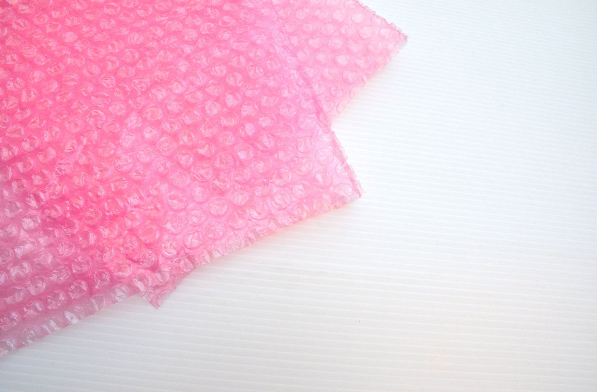 A piece of pink bubble wrap is sitting on a white surface.