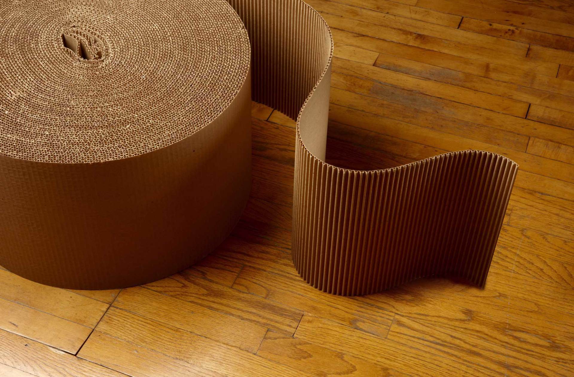 A roll of cardboard is sitting on a wooden floor.