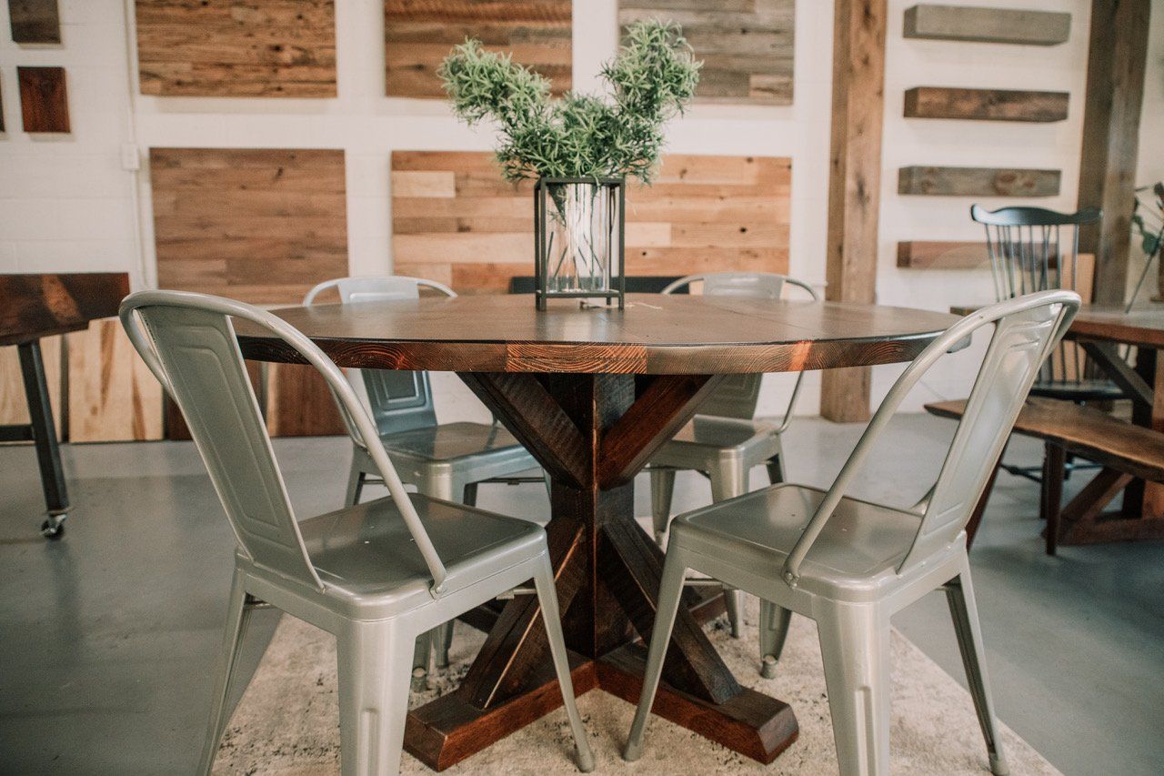 A wooden table and chairs in a room with a vase of flowers on it.