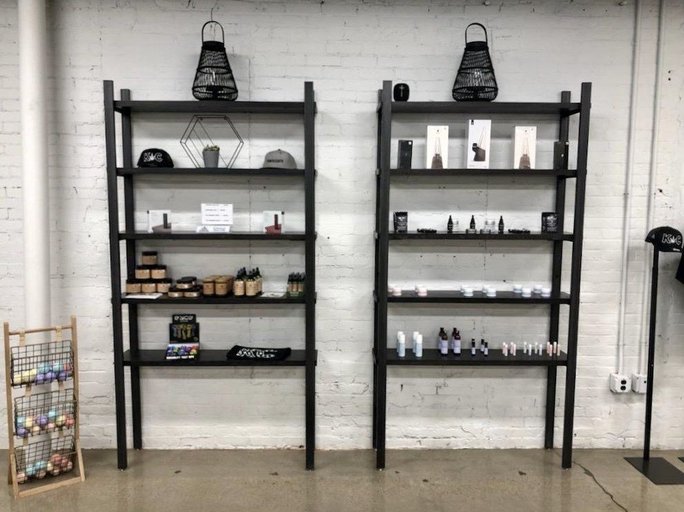 Two black shelves are lined up against a white brick wall.