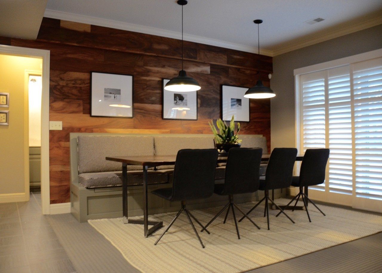 A dining room with a table and chairs and a wooden wall