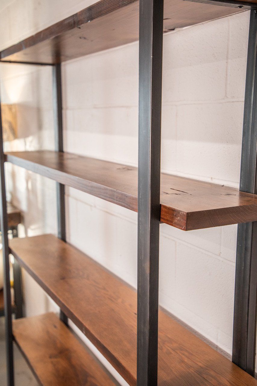 A wooden shelf with a metal frame is against a white wall.