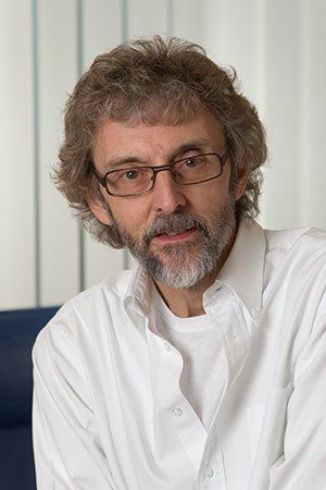 A man with glasses and a beard is wearing a white shirt.