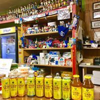Shelves of bottled drinks and snacks inside a small shop with yellow bottles lined across the counter