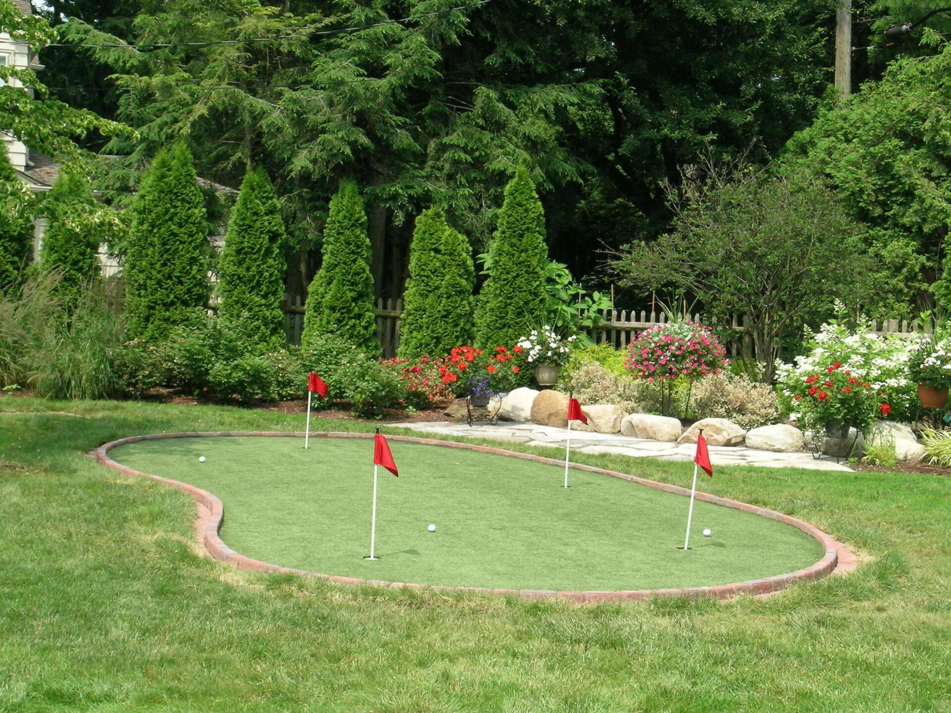 A putting green in a backyard with red flags