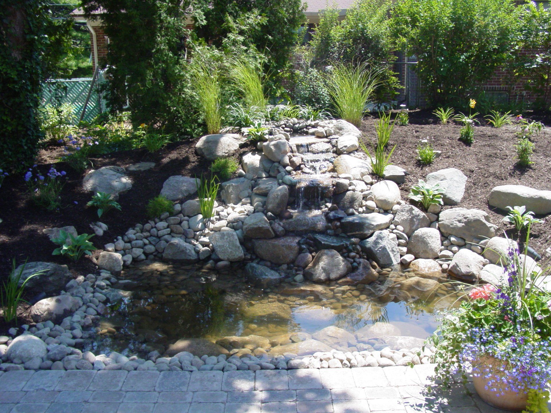 A waterfall is surrounded by rocks and flowers in a garden