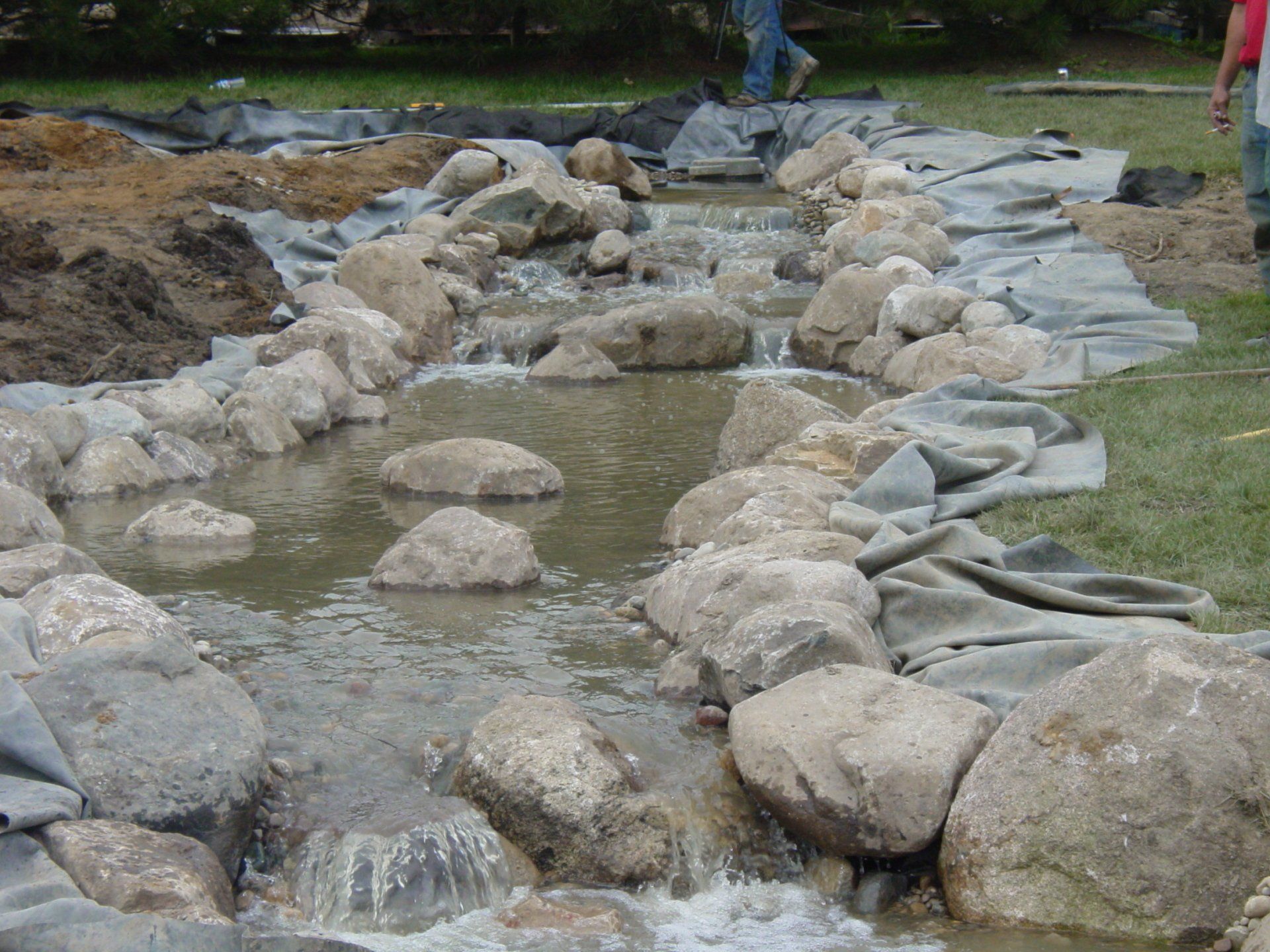A stream of water is surrounded by rocks and grass