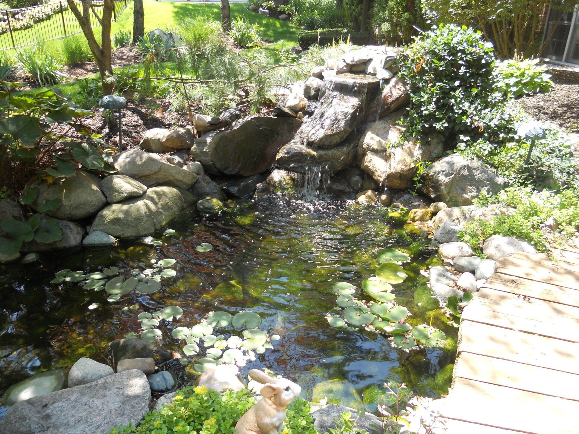 A pond with a waterfall and a bridge in the background